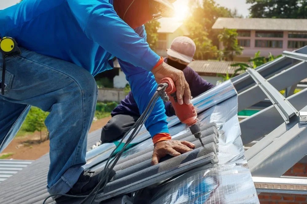 Roofing crew fastening metal roof panels during a repair