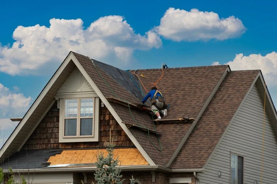 Roofer installing new asphalt shingles on a full roof replacement